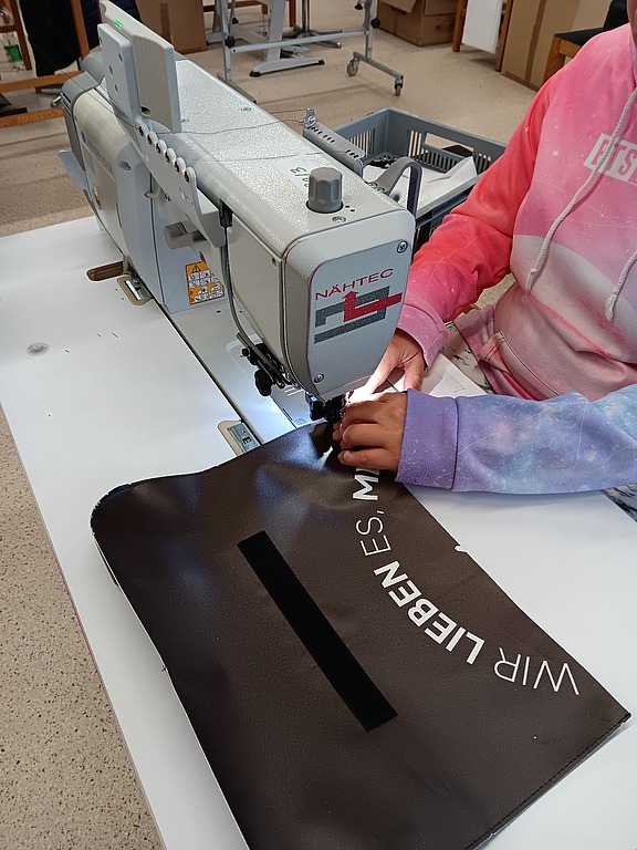 Fertigstellung einer nachhaltigen Laptoptasche im Rahmen des Upcycling-Comebags-Projekt von Hofmann Personal.