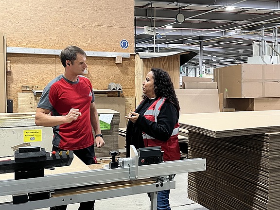 Mitarbeiter im Gespräch mit einer Hofmann-Personalbetreuerin in der Produktionshalle des Verpackungsherstellers