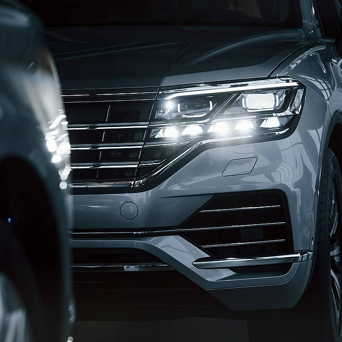 Frontansicht eines weißen Fahrzeugs mit Scheinwerfer symbolisiert Mobilität bei hpm (Hofmann Projektmanagement)