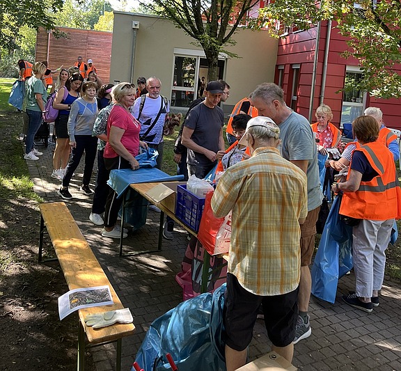 Gruppe von Ehrenamtlichen bei einer Müllsammelaktion, ausgestattet mit Warnwesten und Müllsäcken im Außenbereich