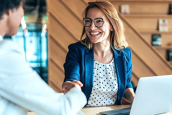 Frau im Büro im Gespräch mit Kollegen symbolisiert Beratung und Zusammenarbeit bei hpm (Hofmann Projektmanagement)
