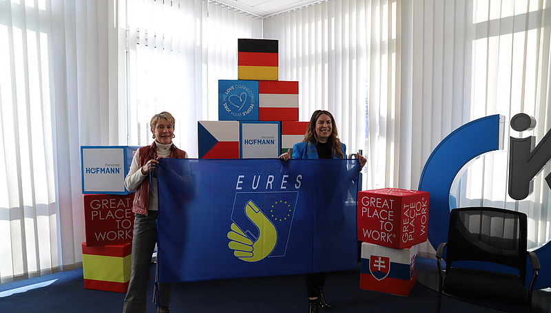 Sonja Heinrich, Mitglied des Executive Committee von Hofmann Personal, hält gemeinsam mit einer weiteren Frau eine EURES-Flagge beim EURES-Jahrestreffen 2026.