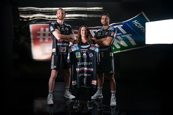 Sonja Heinrich von Hofmann Personal präsentiert mit zwei Handballspielern das HC-Erlangen-Sondertrikot der Vielfalt gewinnt Tour 2026.