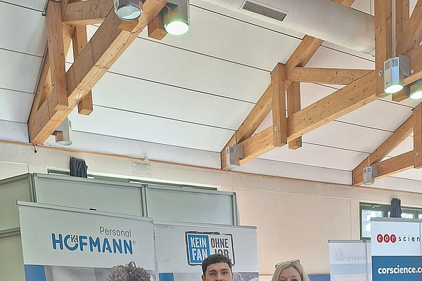 Zwei Mitarbeiter stehen vor dem Messestand von Hofmann Personal beim Tag der Technik 2026 in Erlangen.