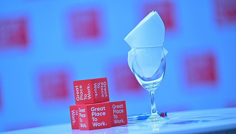 Kleine rote Great-Place-To-Work-Würfel neben einem edlem Glass.
