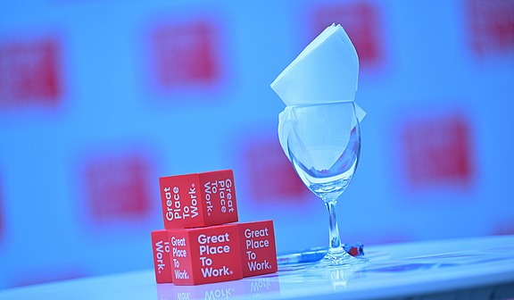 Kleine rote Great-Place-To-Work-Würfel neben einem edlem Glass.