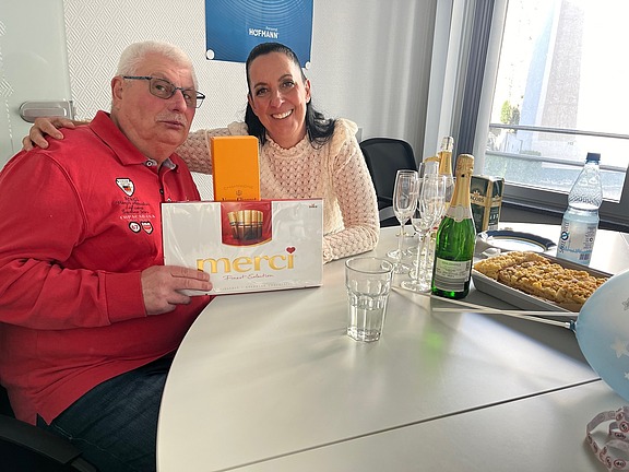 Einem Mitarbeiter wird zum Ruhestand ein Geschenk überreicht, symbolisch für Zusammenhalt und Teamgeist bei Hofmann Personal.