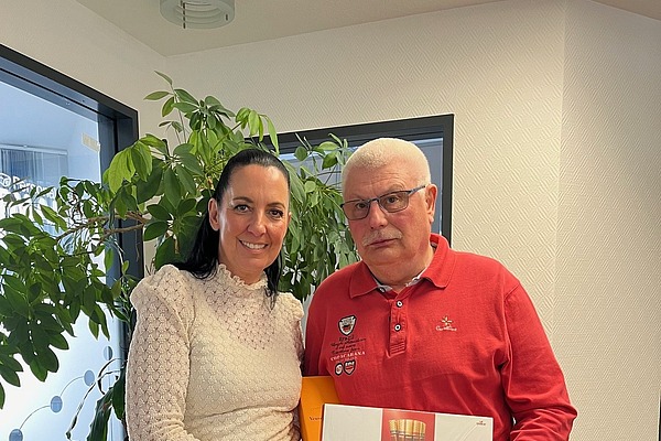 Einem Mitarbeiter wird zum Ruhestand ein Geschenk überreicht, symbolisch für Zusammenhalt und Teamgeist bei Hofmann Personal.
