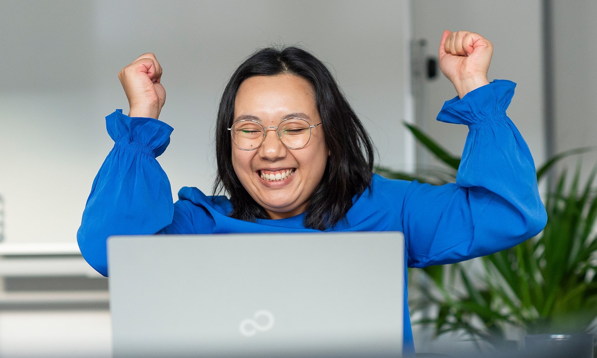 Mitarbeiterin jubelt vor Laptop, symbolisiert Erfolg und Motivation bei medcareer