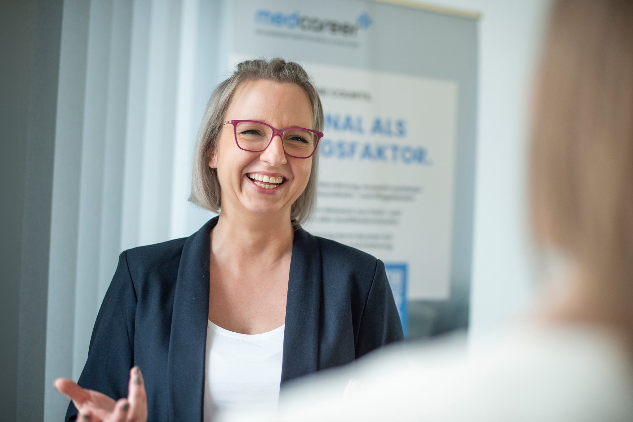 Mitarbeiterin im Gespräch vor medcareer Banner, symbolisiert professionelle Beratung bei medcareer